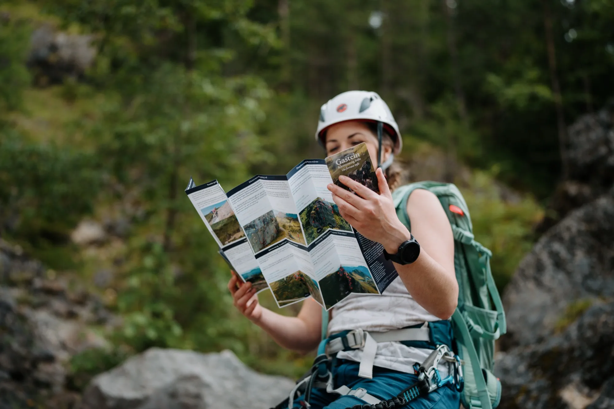 Kletterin liest Klettersteig-Guide Gasteinertal – kompakte Twin-Card Faltkarte mit Routeninfos in der Natur