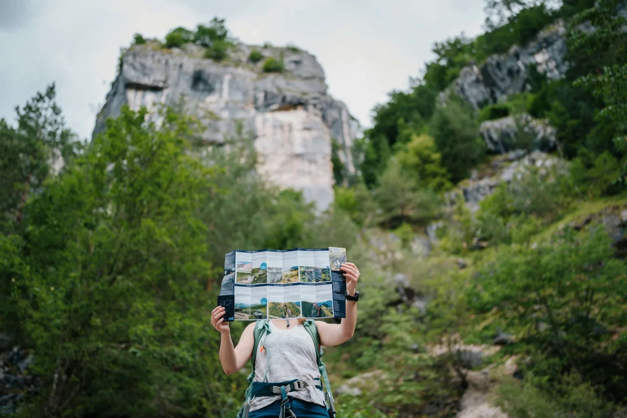 Kletterin hält aufgeklappten Klettersteig-Guide Gasteinertal vor imposanter Felswand – Outdoor-Faltkarte im Einsatz