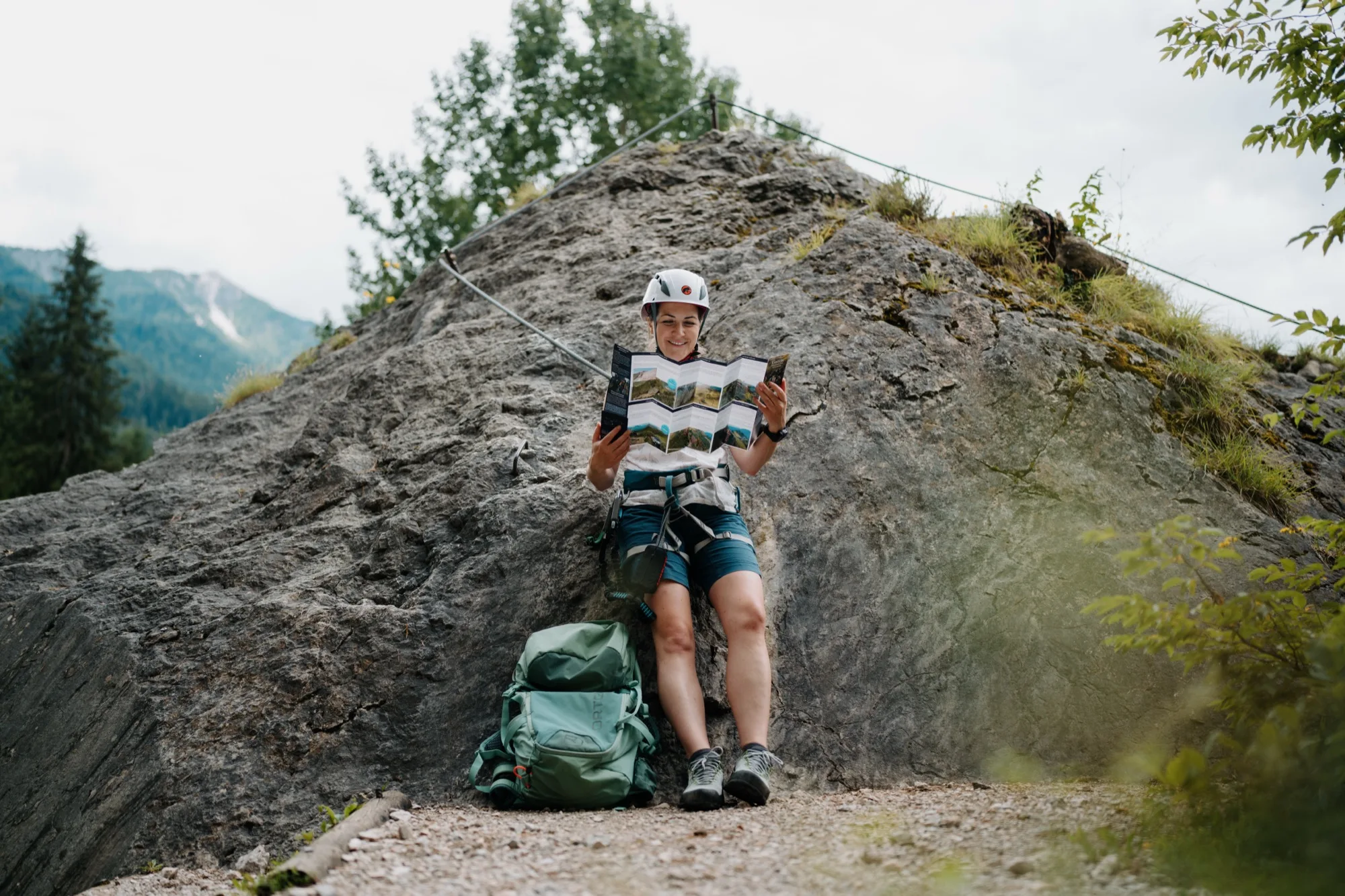 Klettersteiggeherin liest aufgefaltete Twin-Card mit Routeninformationen am Klettersteig im Gasteinertal