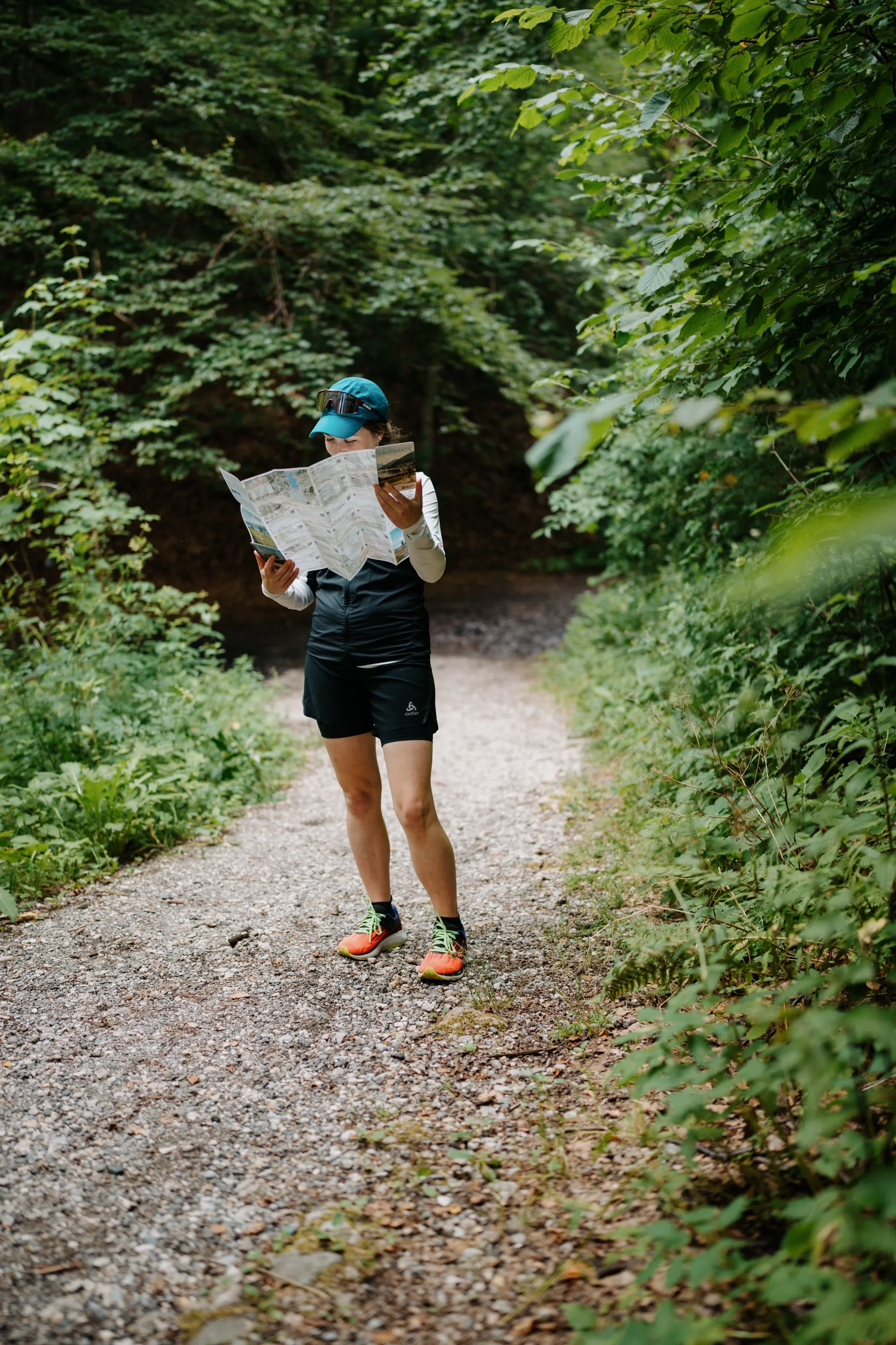 Laufkarte Zell am See-Kaprun in Action – Läuferin liest Faltkarte auf Waldweg